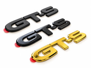 Reproduction GT-S emblem for the 1991–1999 Toyota MR2 SW20 in unpainted matte black, painted gloss black, and gold chrome